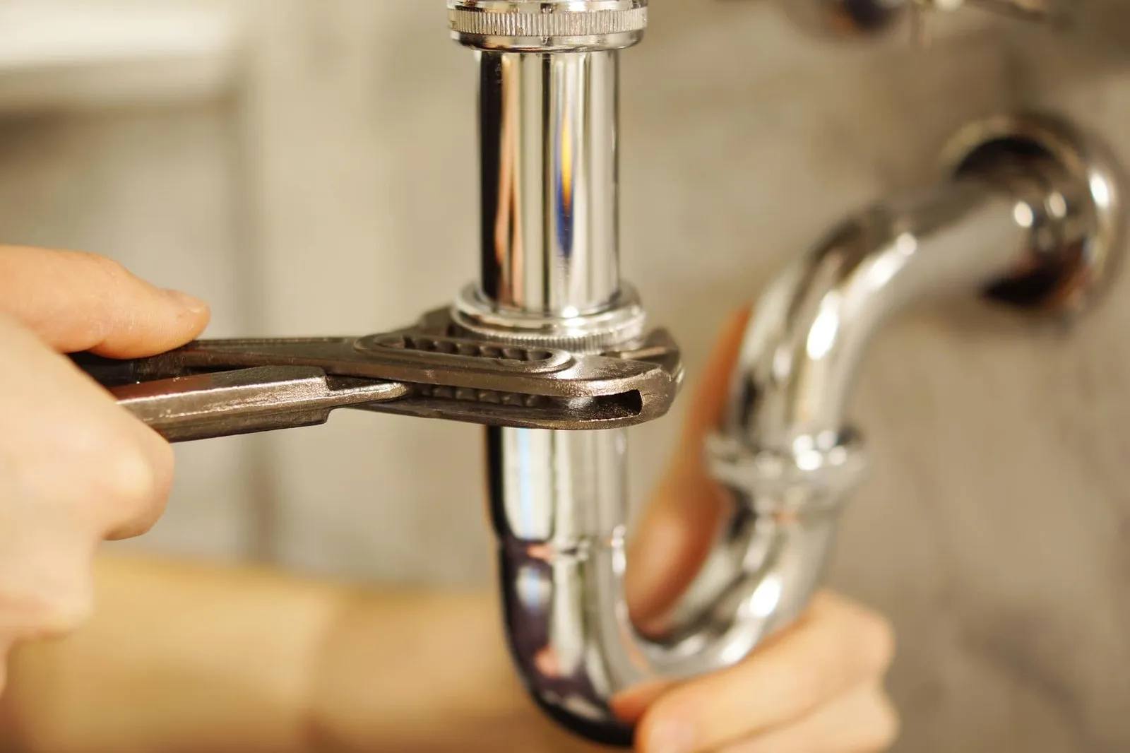 Clé serrée sur un siphon de plomberie lors d’une réparation.