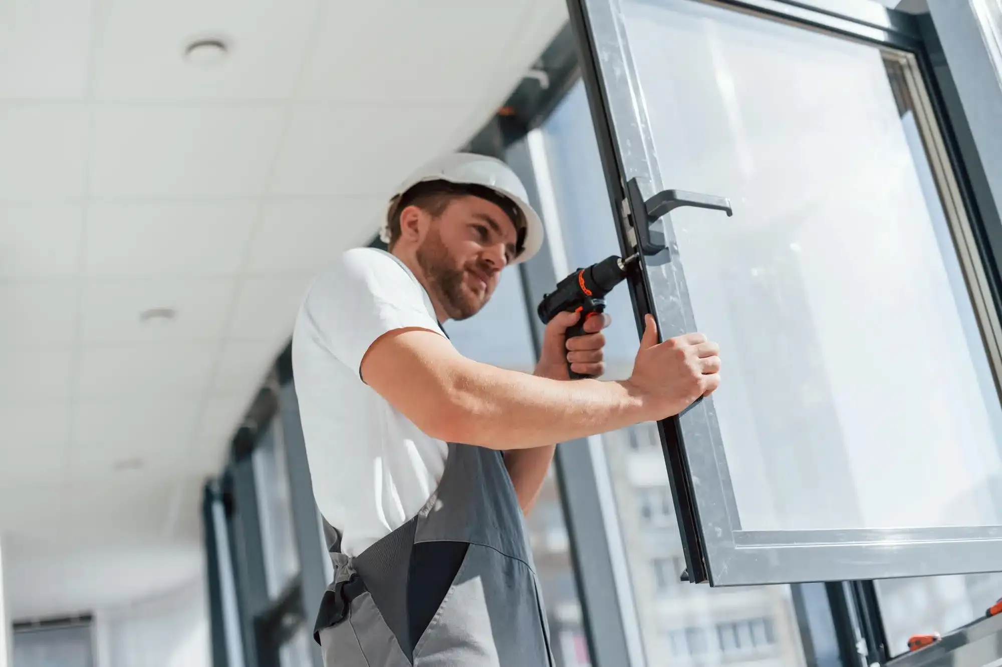 Pose d’un châssis vitré à la perceuse.